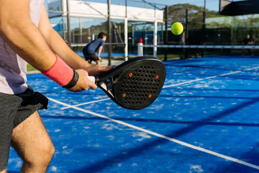 Padel hráč s pálkou na modrém kurtu